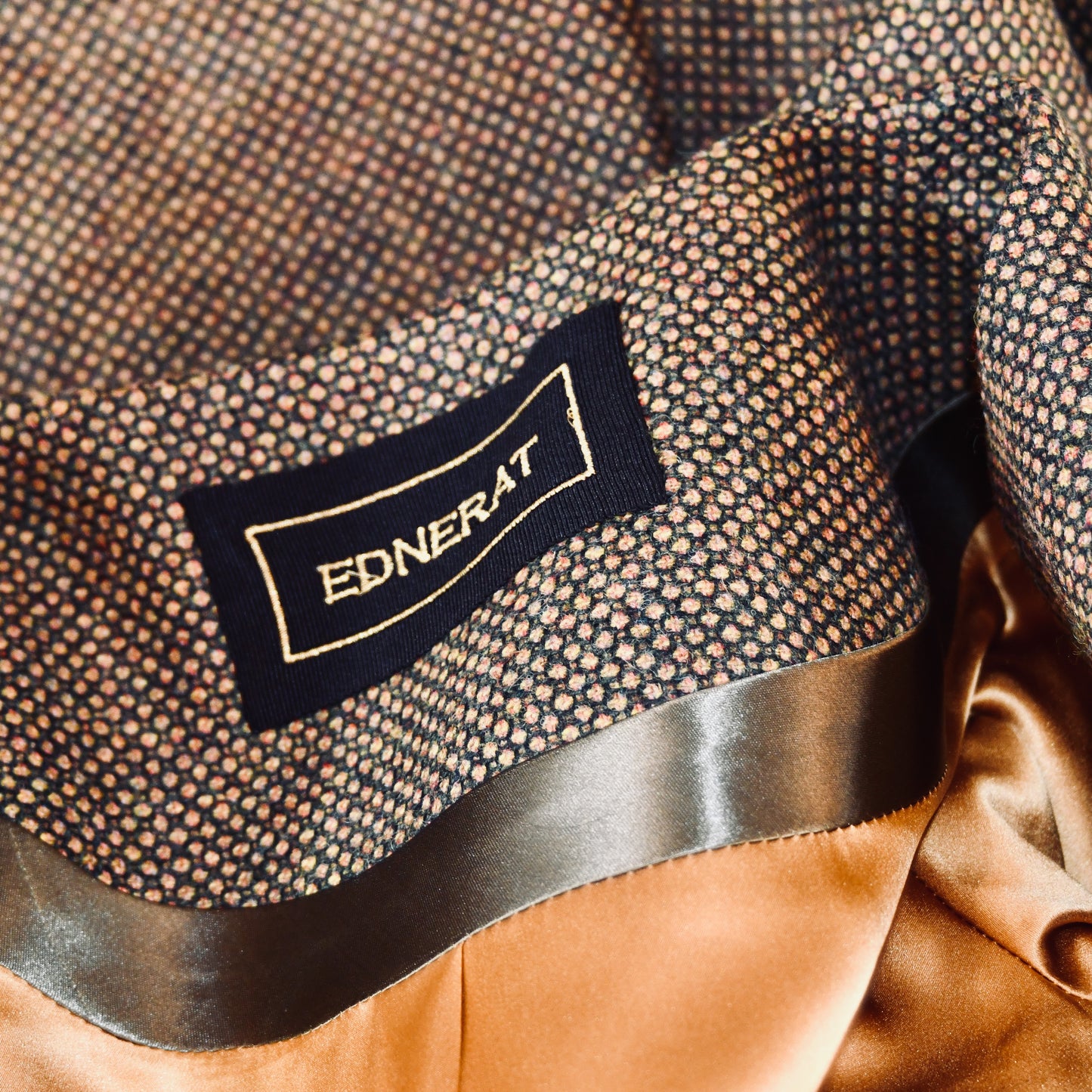 Bespoke Bell Sleeve A-Line Coat in Green and Orange Patterned Tweed. A longer length A-Line coat in a wonderfully elegant patterned tweed with shoulder and sleeve cuff details. Perfect for winter racing. Entirely made in Great Britain. Collar Detail showing embroidered label and gold lining.
