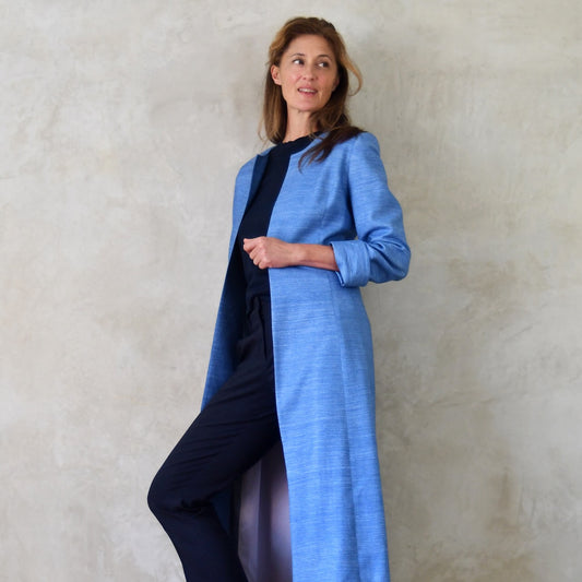 Tailored, Fitted Hourglass shaped coat in a summer-weight Silk Madras in Blue. This is a long-sleeved, calf-length blue summer coat with an hourglass shape. Full Length Shot. A perfect summer coat for weddings and special occasions. Handmade in Britain.