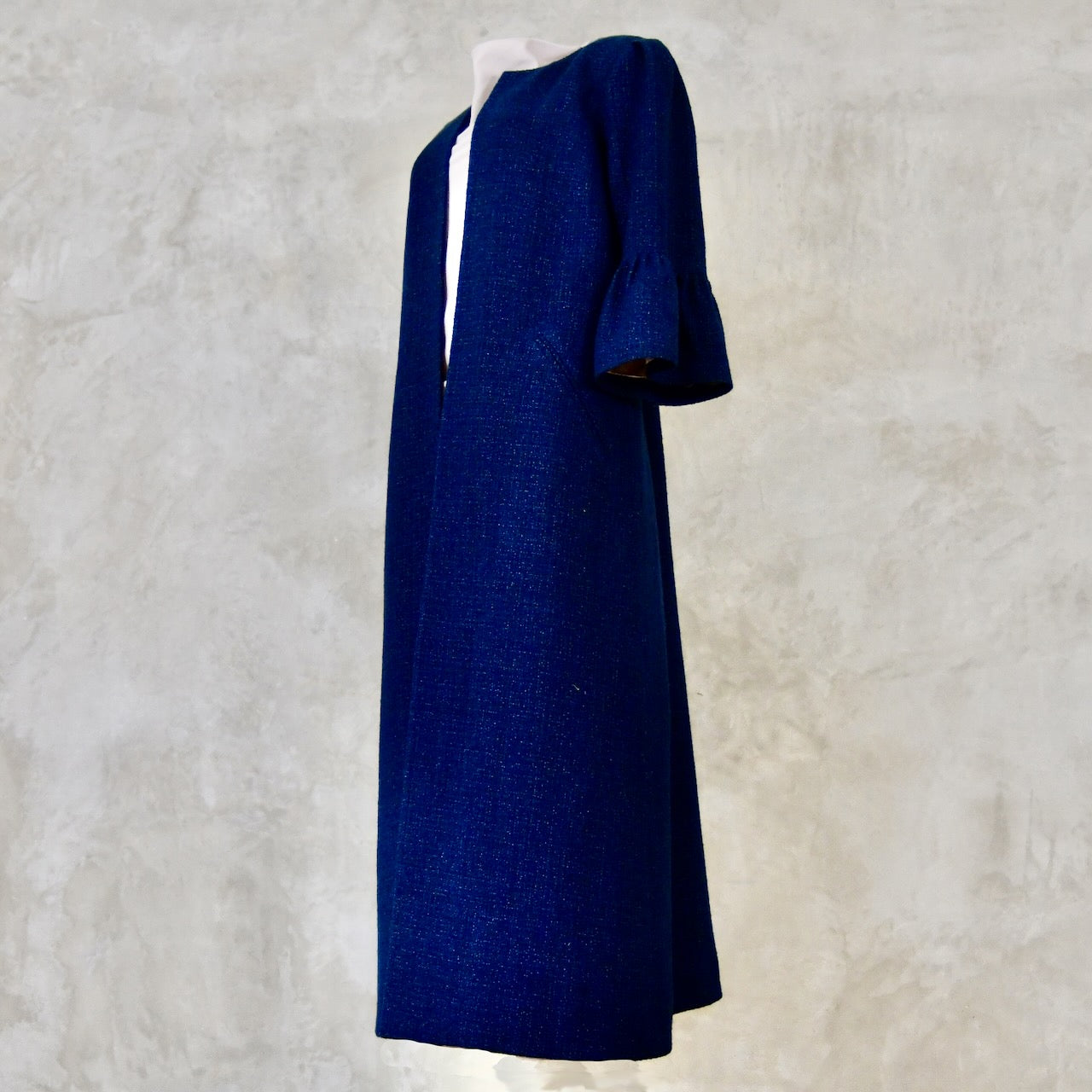 A Bespoke Bell Sleeved A Line Coat in Navy, Black and White Cotton Boucle from Linton Tweeds. A minimalist but elegant summer coat with three-quarter bell sleeves and an A-Line design. Handmade in Britain.