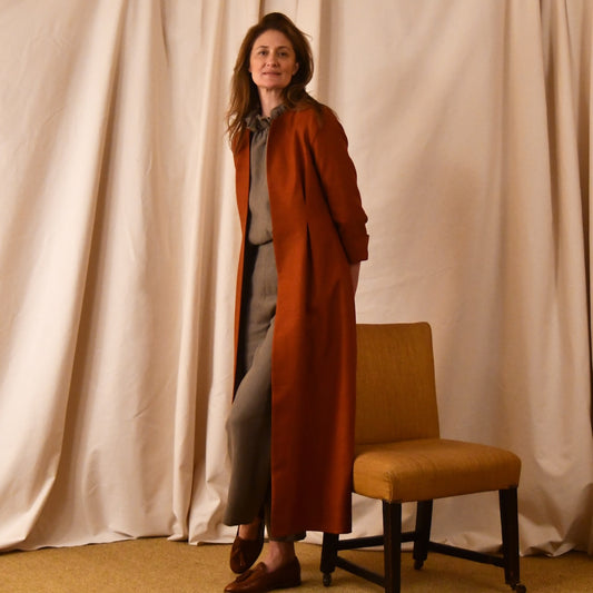 Tailored, Fitted Hourglass shaped coat in a summer-weight Silk in a terracotta colour. This is a three-quarter-sleeved, calf-length blue summer coat with an hourglass and skirted shape. Shown open. A perfect summer coat for weddings and special occasions. Handmade in Britain.