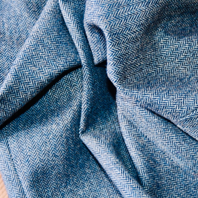 Fabric Close of EdNerat's Denim Blue Tweed Herringbone Tweed. Used on its A-Line Bell Sleeve Coat the shot of this Yorkshire fabric shows its herringbone pattern and detailed folds. Handmade in Britain.