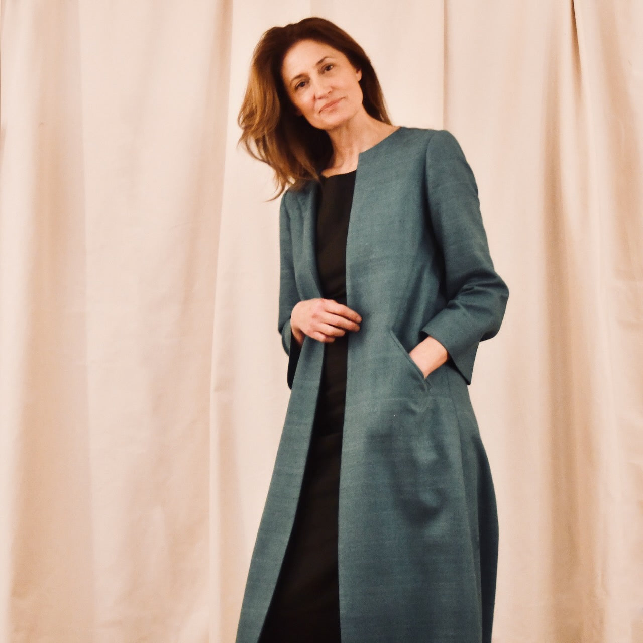 Silk Matka A-Line Coat in teal over a black dress. Handmade in Britain.