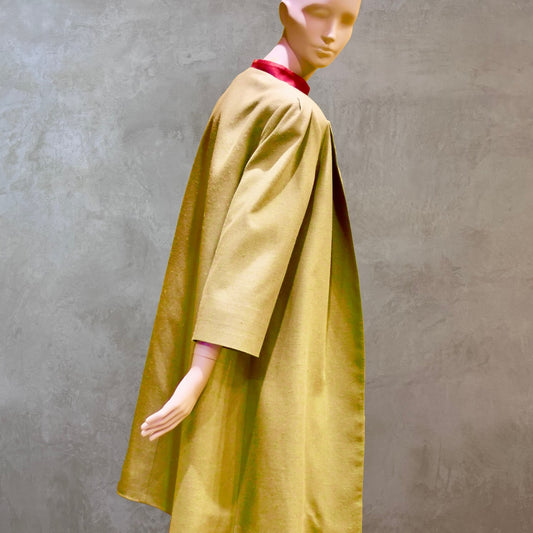 Side Rear view of Silk car coat in lime green. This is a Mid length coat with shoulder detail in an easy to wear trapeze shape. Fully lined in silk and made by hand in London.