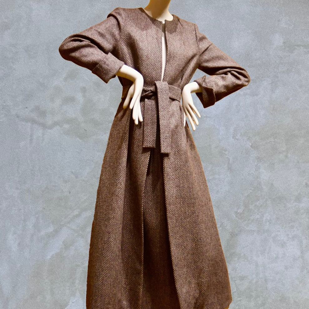 Long fitted tweed coat in pink colour. The ankle-length coat showcases a gray-pink textured tweed, hourglass tailoring, fitted seams, and back tucks. Handmade in Britain.