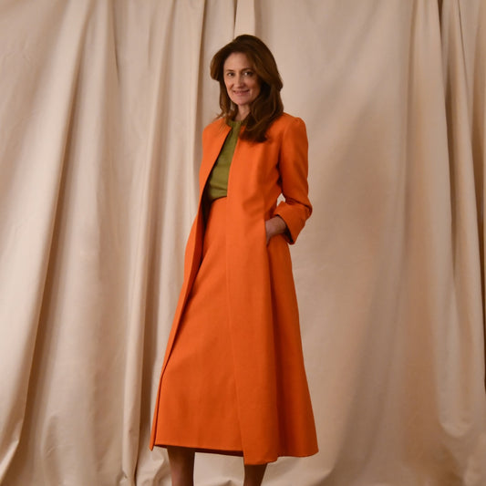 Tailored, Fitted, Hourglass Coat in Orange Silk Matka. The coat is shown worn open in an elegant and relaxed look. Handmade in Britain.