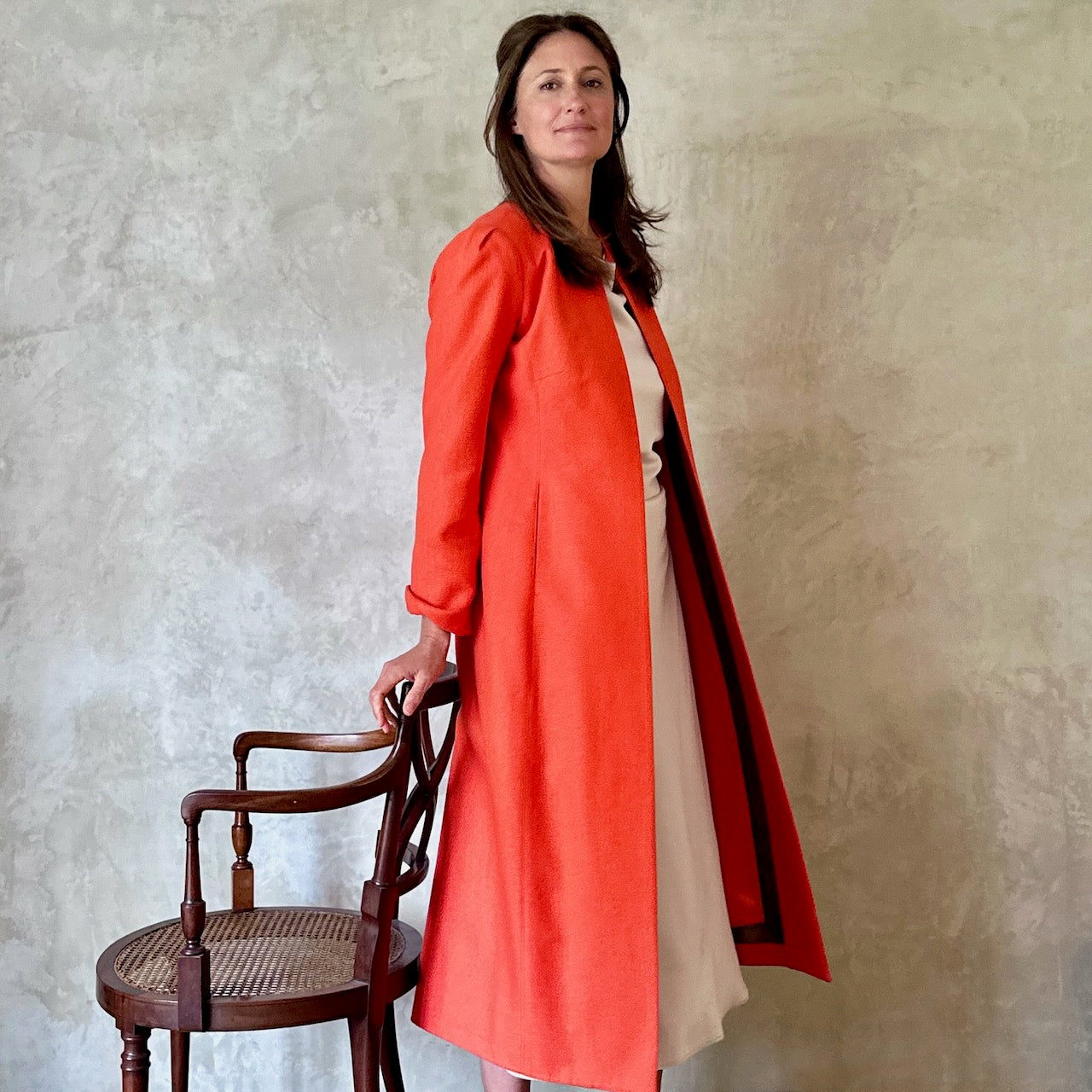 Tailored, Fitted, Hourglass Coat in Orange Silk Matka. The coat is shown worn open in an elegant and relaxed look. Handmade in Britain.