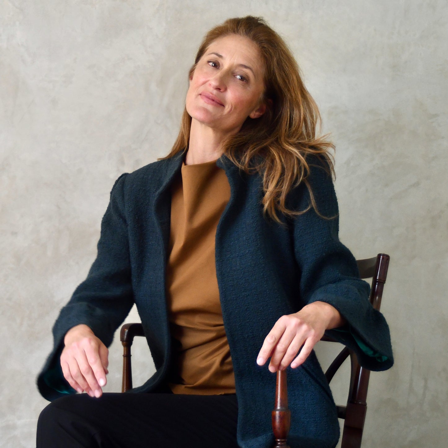 Bell Sleeve A-Line Coat in Bottle Green Linton Tweeds Boucle An elegant and easy-to-wear longer length A-line coat with frill cuff details in a warmer weight deep green wool bouclé. Entirely made in Great Britain. Seated.