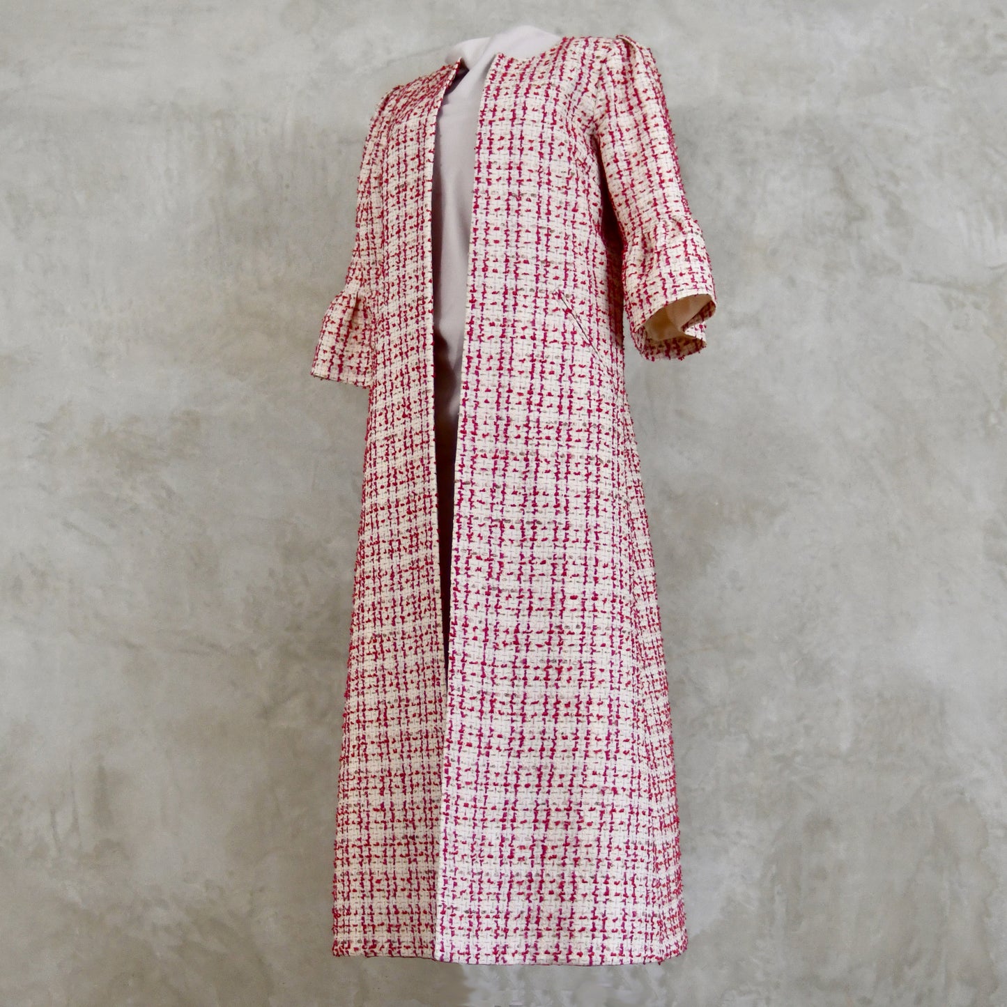 Bell Sleeve A-Line Coat in Pink Patterned Linton Tweeds Boucle. A pretty, longer length A-line coat in a pink, cream and gold check pattern for smart spring and summer occasions. Entirely made in Great Britain. Full View.