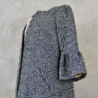 A Longer length Bell Sleeve A-Line Coat in Black and OffWhite Linton Tweeds Boucle
This is an elegant longer length A-Line coat in a patterned boucle from Carlisle. With a magnificent drape and delicate sleeve and shoulder detailing, this coat will take you everywhere. Handmade in Britain. Close Up