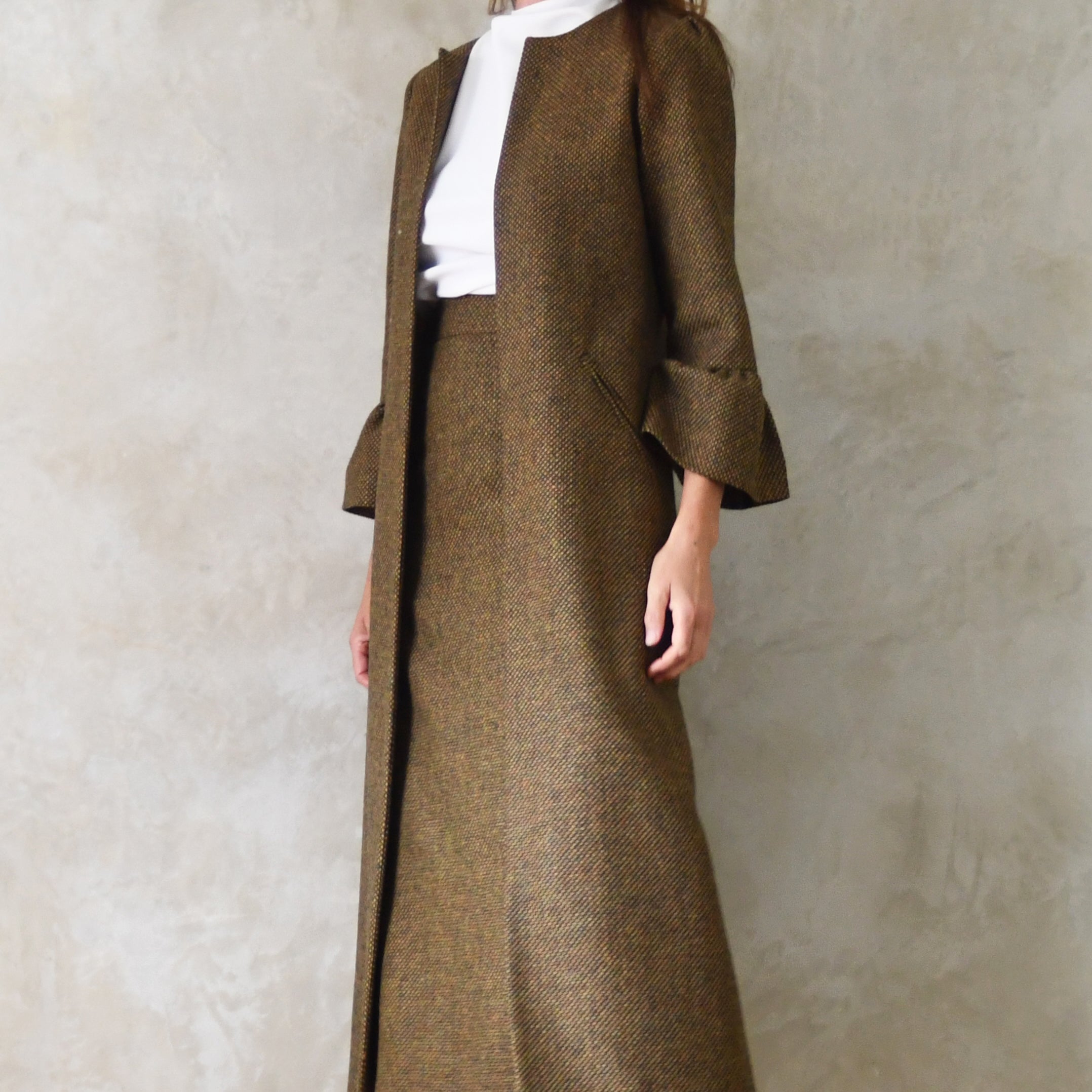 Bespoke Bell Sleeve A-Line Coat in Green and Orange Patterned Tweed. A longer length A-Line coat in a wonderfully elegant patterned tweed with shoulder and sleeve cuff details. Perfect for winter racing. Entirely made in Great Britain. Close up on Tweed Skirt Suit.