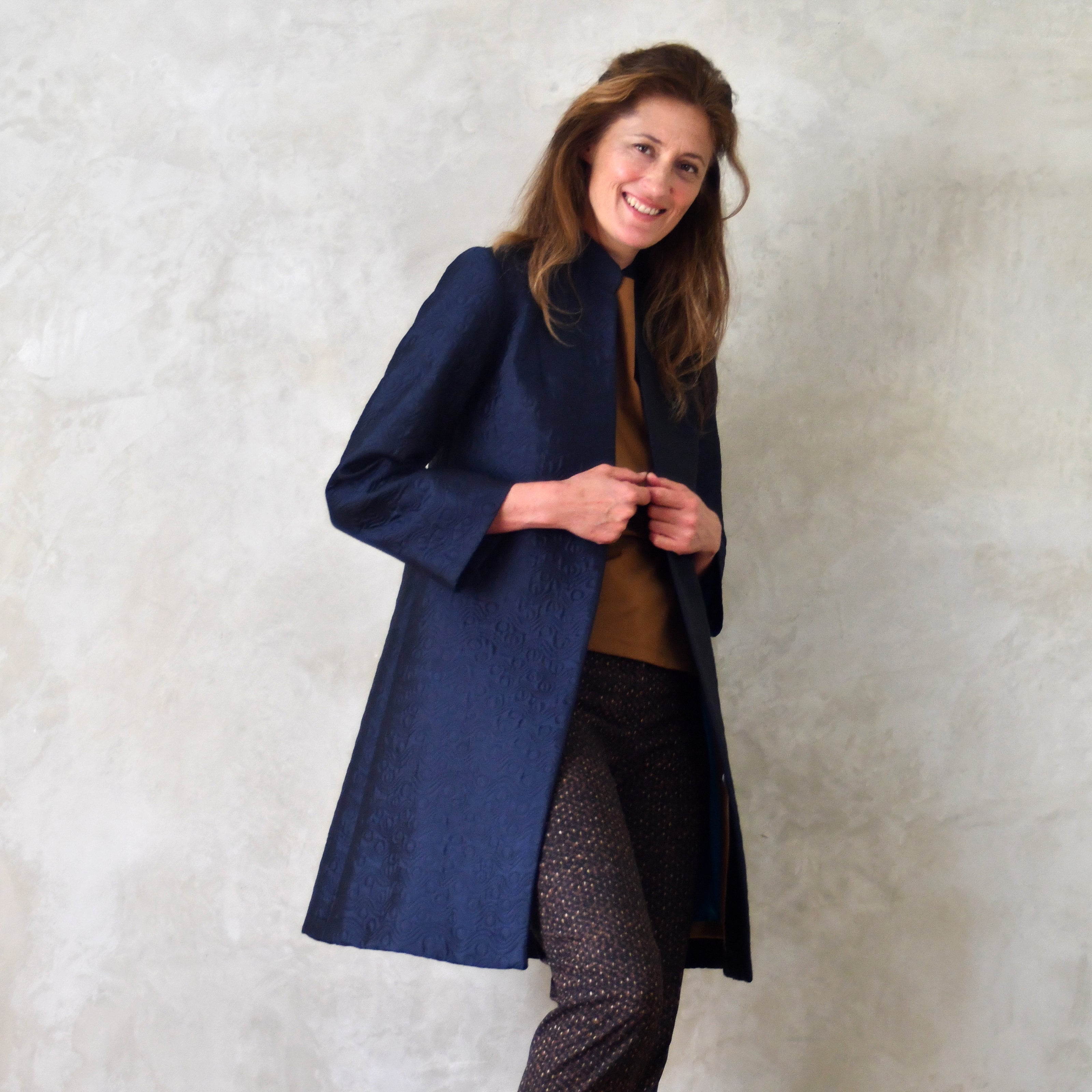 Bespoke Trapeze Coat in Dark Navy Bubble Brocade. The perfect mid length alternative to jacket, this rich navy brocade is elegant, packable and easy to wear. Entirely made in Great Britain. Close Up.
