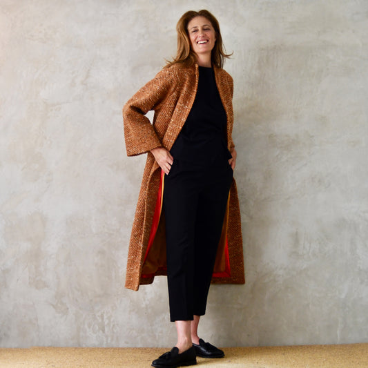 Longer Length Cocoon Coat in Burnt Orange Linton Tweeds Boucle. A hugely versatile Mid Season coat in a patterned wool-mix bouclé that can be dressed up or down and will work as well in town as in the country. Handmade in Britain. Front Open View, Hands in Pockets.