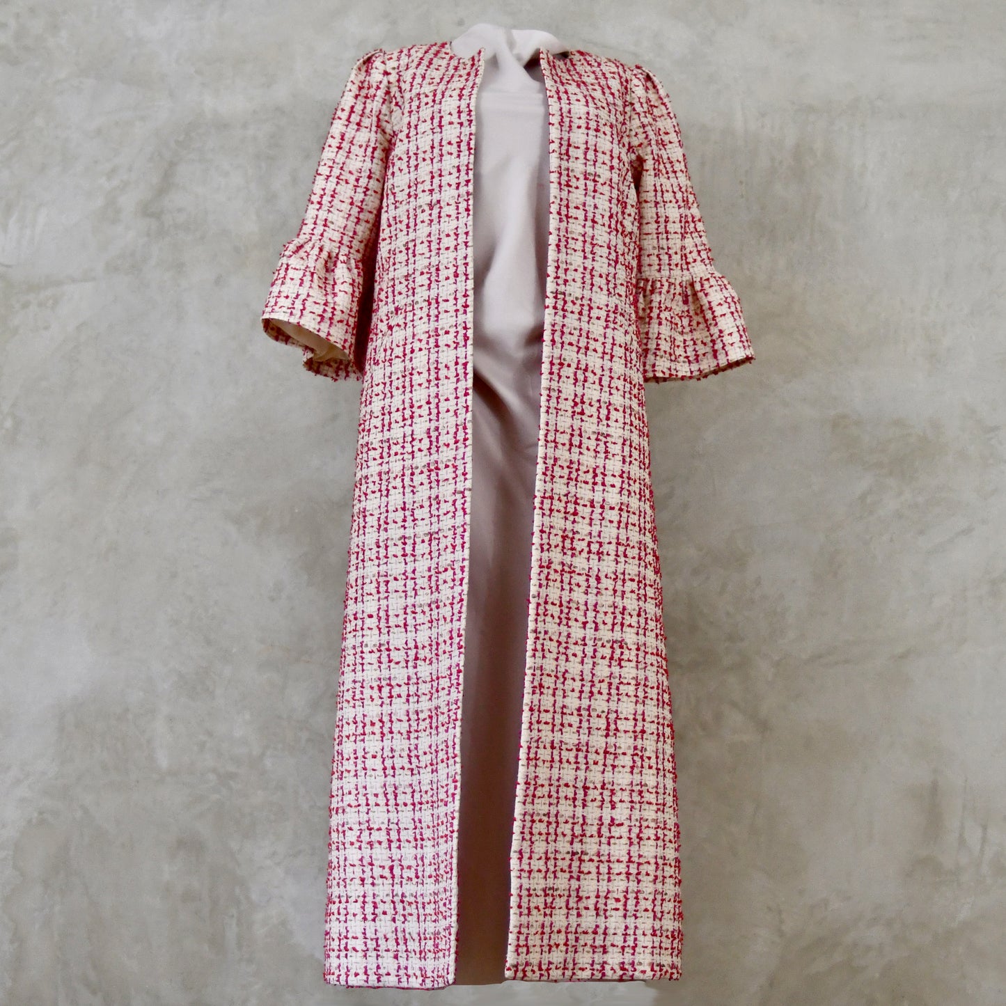 Bell Sleeve A-Line Coat in Pink Patterned Linton Tweeds Boucle. A pretty, longer length A-line coat in a pink, cream and gold check pattern for smart spring and summer occasions. Entirely made in Great Britain. Front View.