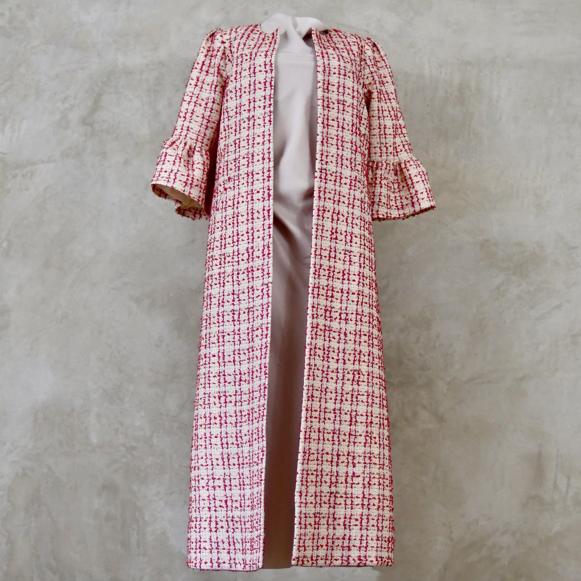 Bell Sleeve A-Line Coat in Pink Patterned Linton Tweeds Boucle. A pretty, longer length A-line coat in a pink, cream and gold check pattern for smart spring and summer occasions. Entirely made in Great Britain. Front View.