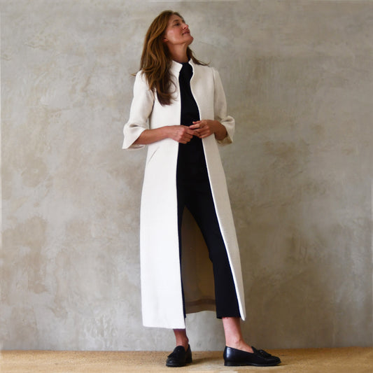Long White Silk Coat With Bell Sleeves. An A Line Shape elegant coat in pure silk. Nehru collar, gathered cuffs on sleeves and slanted pockets to front. Handmade in Britain. Bespoke options available.