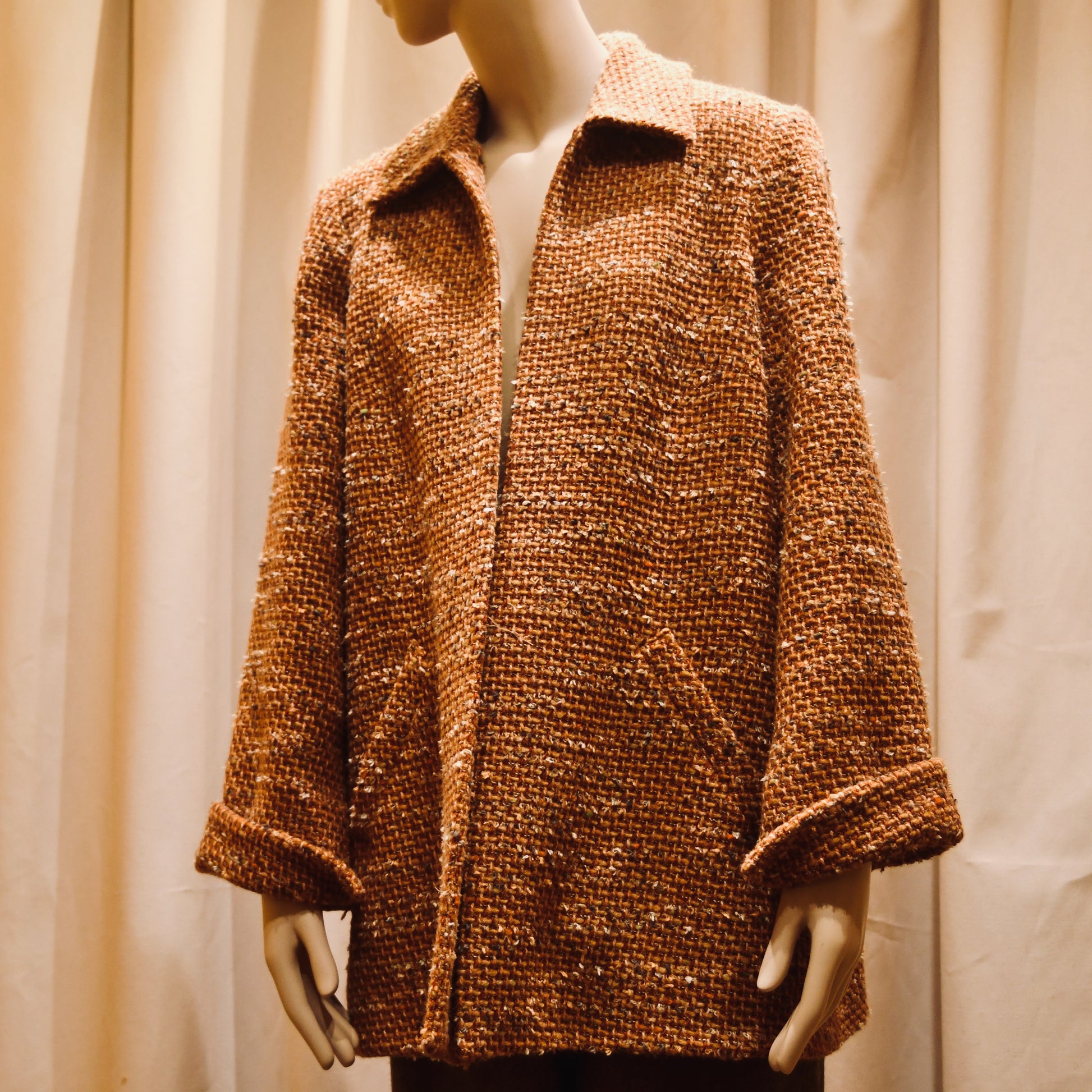 Bespoke Tailored Swing Jacket in Burnt Orange Wool Mix Bouclé from Linton Tweeds. A women’s long-sleeve, collared coat with slanted front pockets. Sophisticated and easy, the jacket is shown from the side. Handmade in Britain.