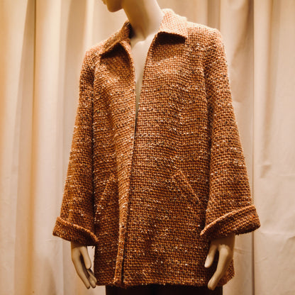 Bespoke Tailored Swing Jacket in Burnt Orange Wool Mix Bouclé from Linton Tweeds. A women’s long-sleeve, collared coat with slanted front pockets. Sophisticated and easy, the jacket is shown from the side. Handmade in Britain.