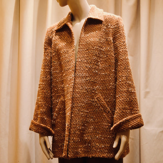 Bespoke Tailored Swing Jacket in Burnt Orange Wool Mix Bouclé from Linton Tweeds. A women’s long-sleeve, collared coat with slanted front pockets. Sophisticated and easy, the jacket is shown from the side. Handmade in Britain.
