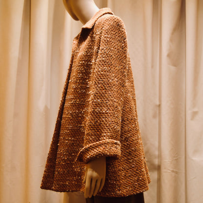 Tailored Swing Jacket in Burnt Orange Wool Mix Bouclé from Linton Tweeds. This bespoke jacket has rolled cuffs and a textured finish and a flared silhouette. Viewed from the back. Handmade in Britain.
