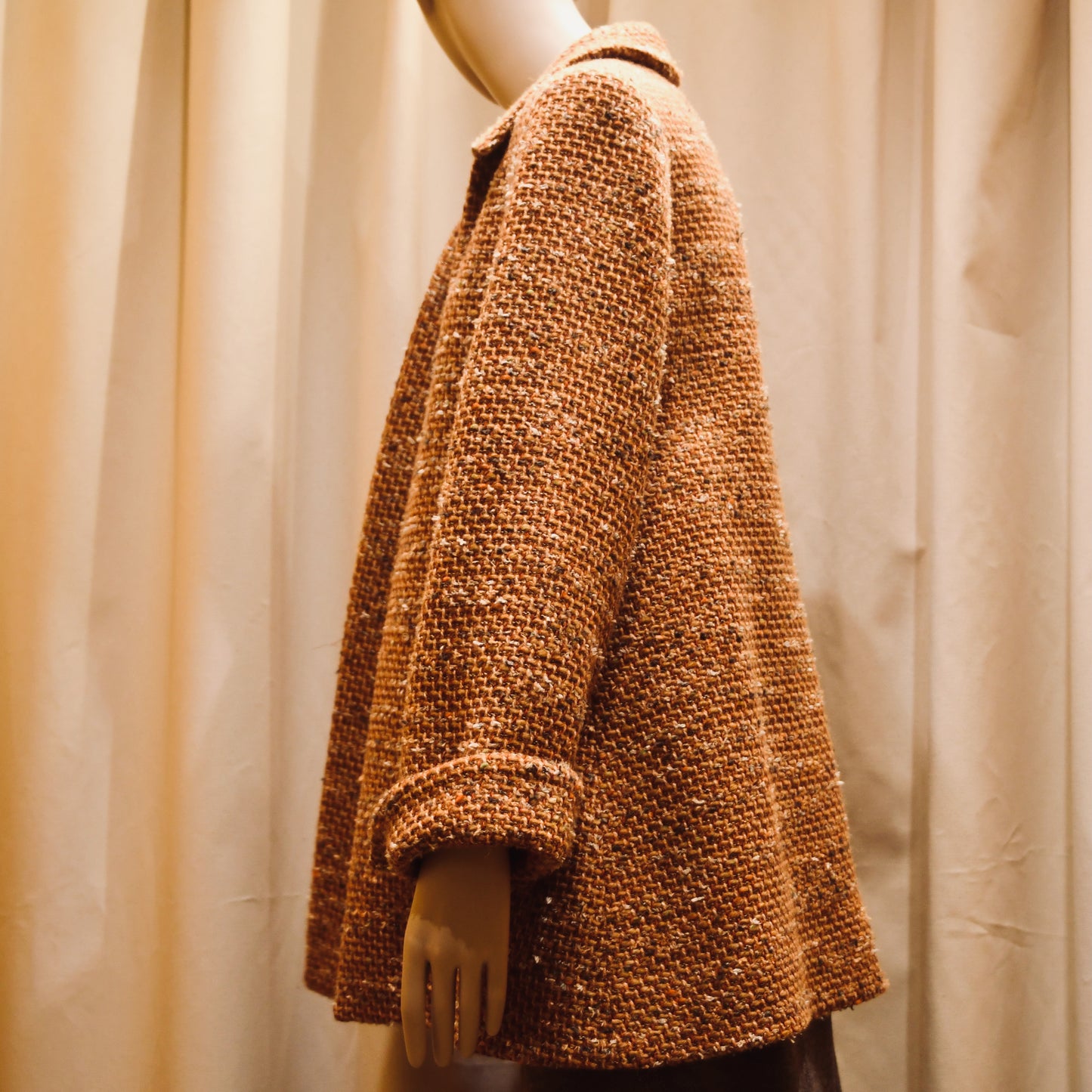 Trapeze Swing Jacket in Burnt Orange Wool Mix Bouclé from Linton Tweeds, featuring textured fabric and a side pocket. This loose fitting tailored jacket is shown from the side. Handmade in Britain.