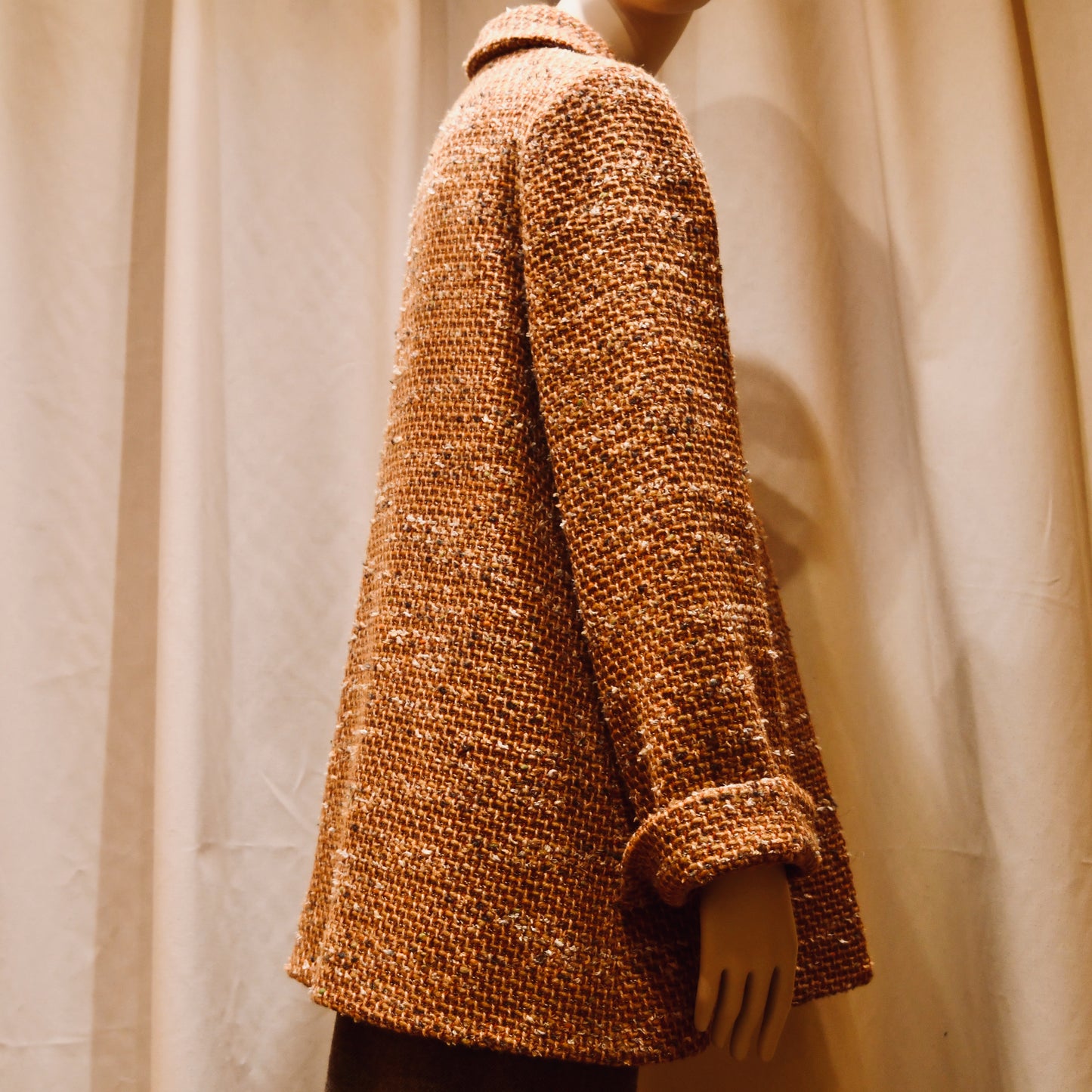 Tailored Swing Jacket in Burnt Orange Wool Mix Bouclé from Linton Tweeds. This bespoke jacket has rolled cuffs and a textured finish and a flared silhouette. Shown  turned to the side. Handmade in Britain.