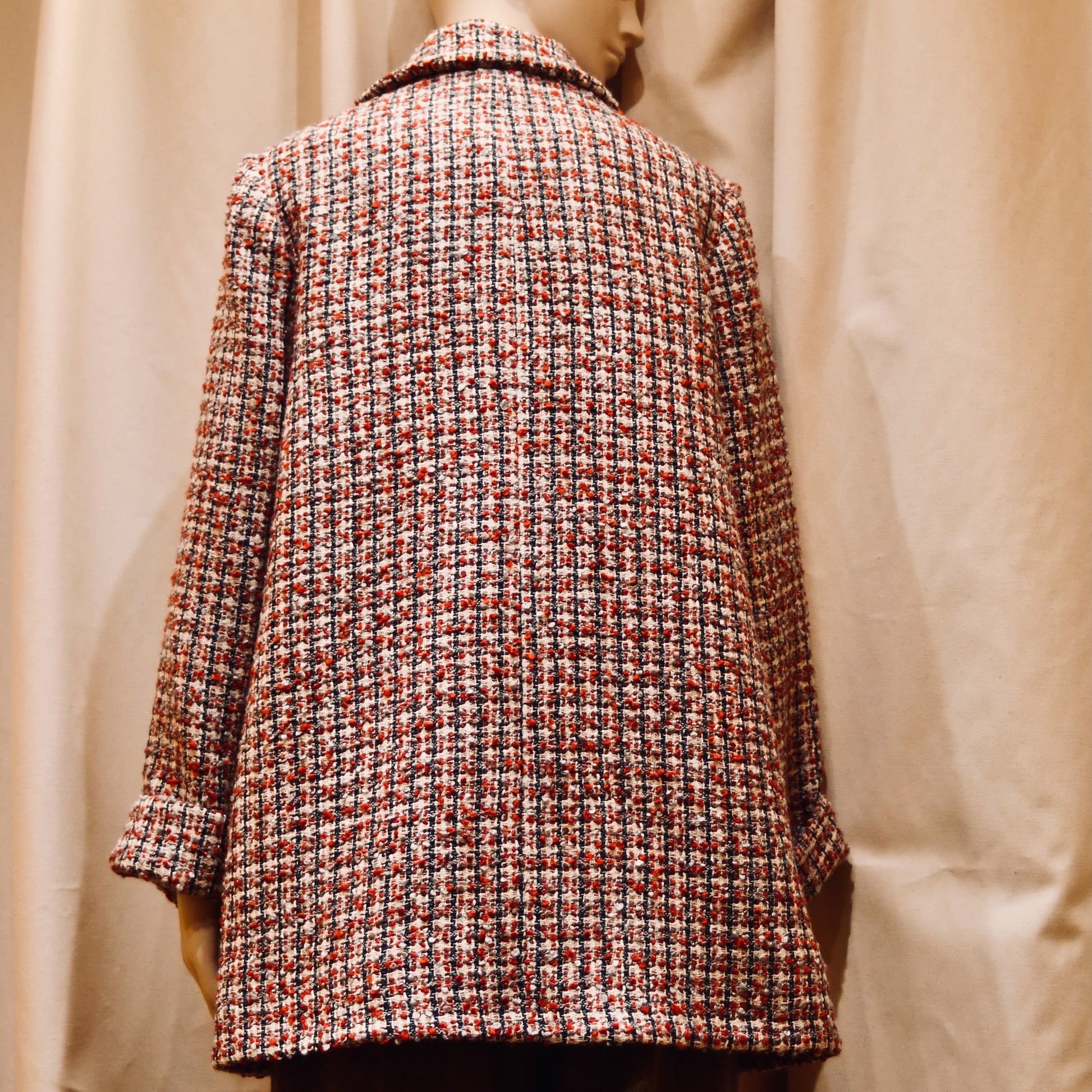 Bespoke Trapeze Swing Jacket in red, ecru, and navy Wool Bouclé from Linton Tweeds. With long sleeves and a collar,  it is shown viewed from the back. Handmade in Britain.
