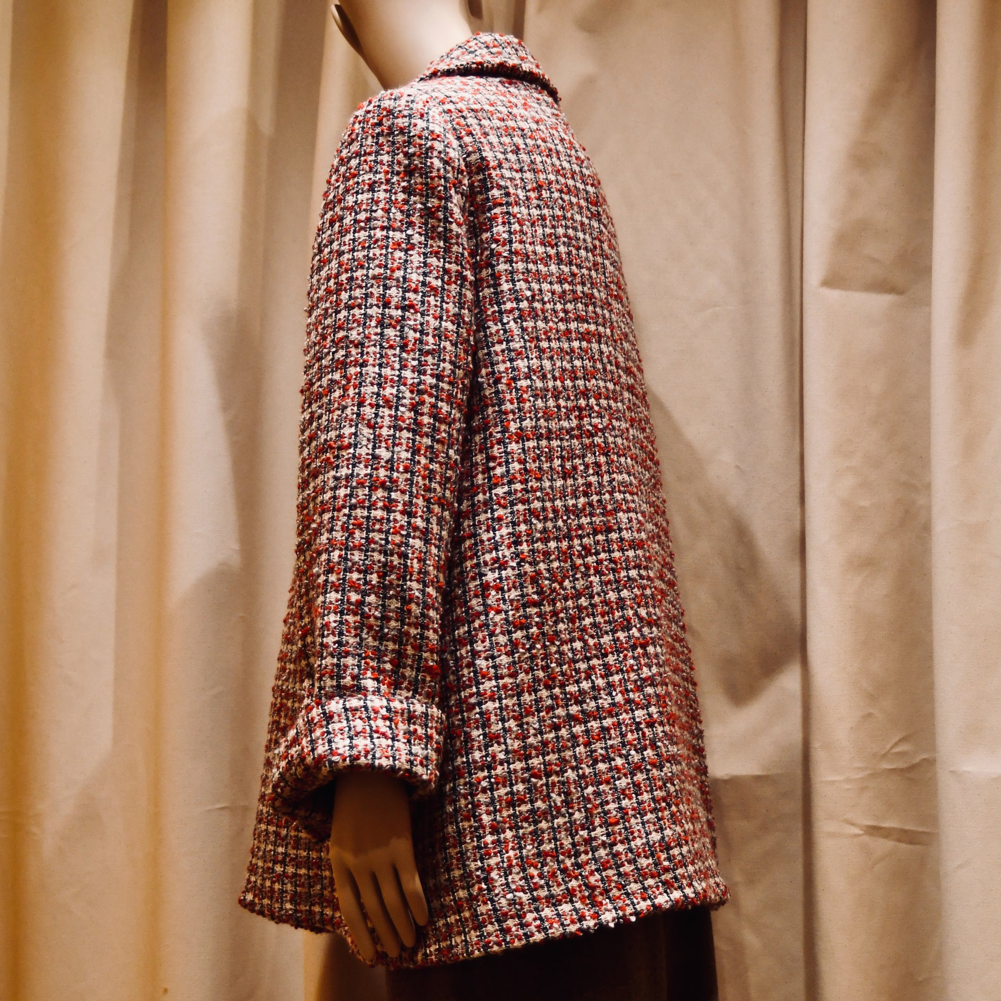 Bespoke Trapeze Swing Jacket in red, ecru, and navy Wool Bouclé from Linton Tweeds. With long sleeves and a collar,  it is shown viewed from the back. Handmade in Britain.