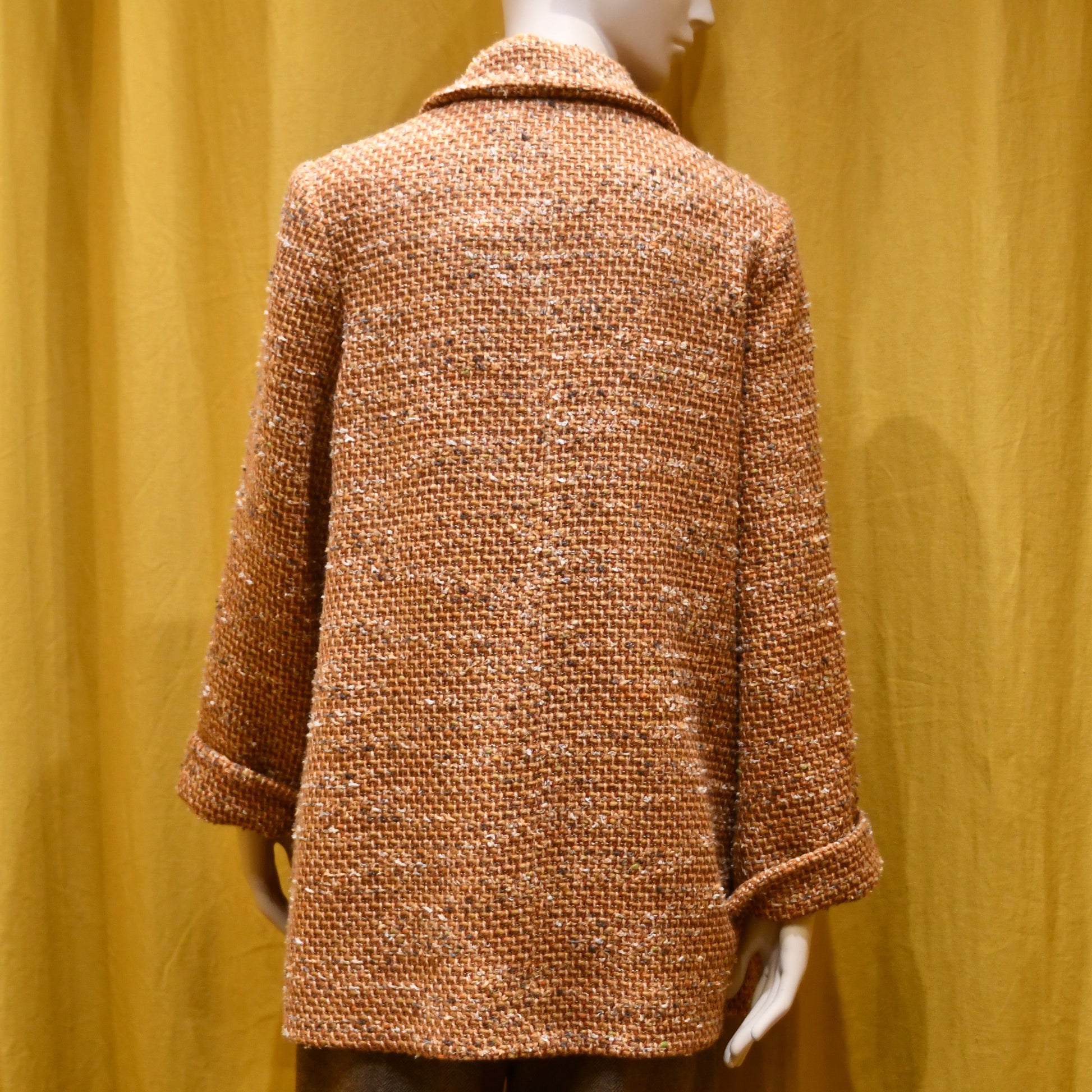 Trapeze Swing Jacket in Burnt Orange Wool Mix Bouclé from Linton Tweeds, featuring textured fabric and a side pocket. Rear View. Handmade in Britain.