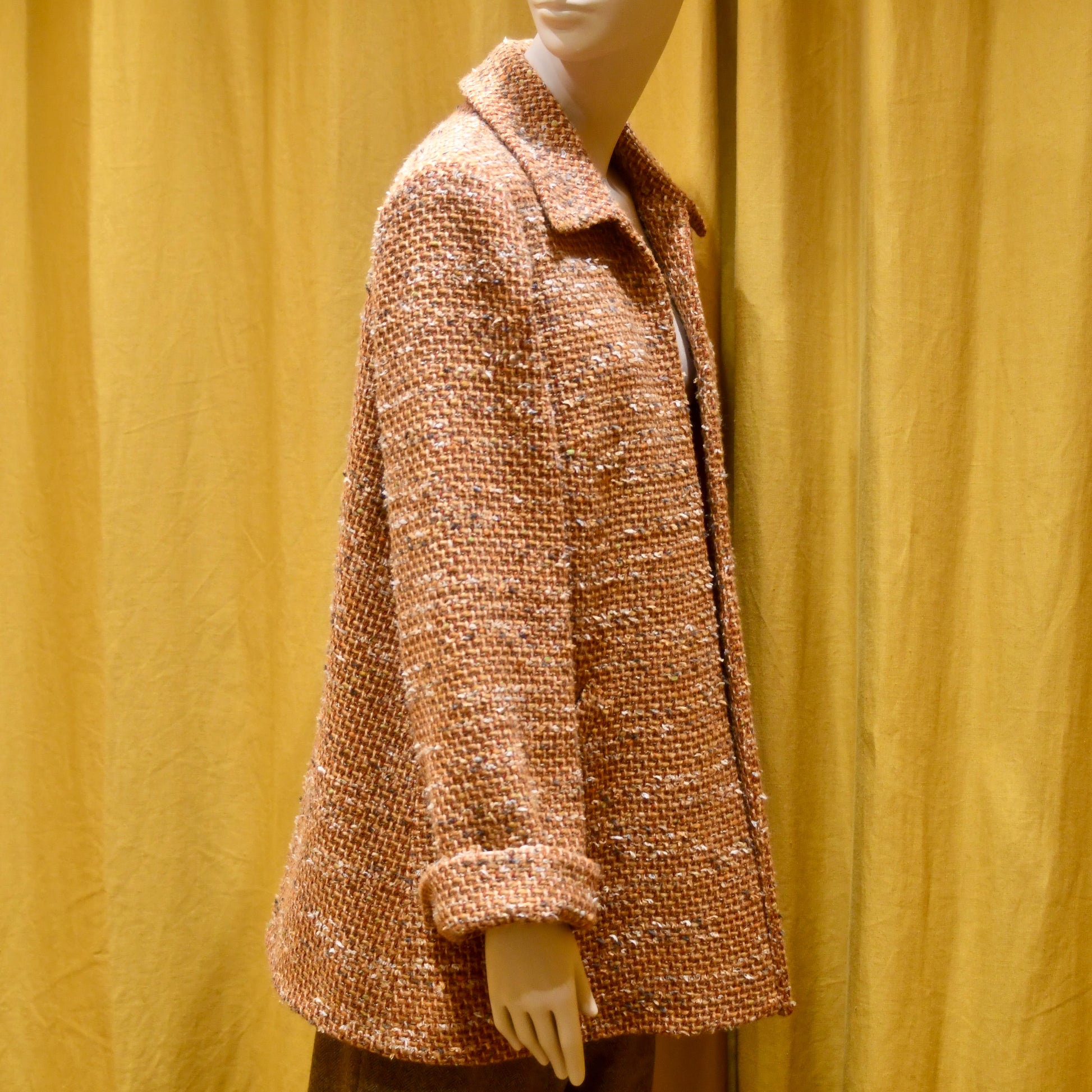 Tailored Swing Jacket in Burnt Orange Wool Mix Bouclé from Linton Tweeds. This bespoke jacket has rolled cuffs and a textured finish and a flared silhouette. Shown side on. Handmade in Britain.