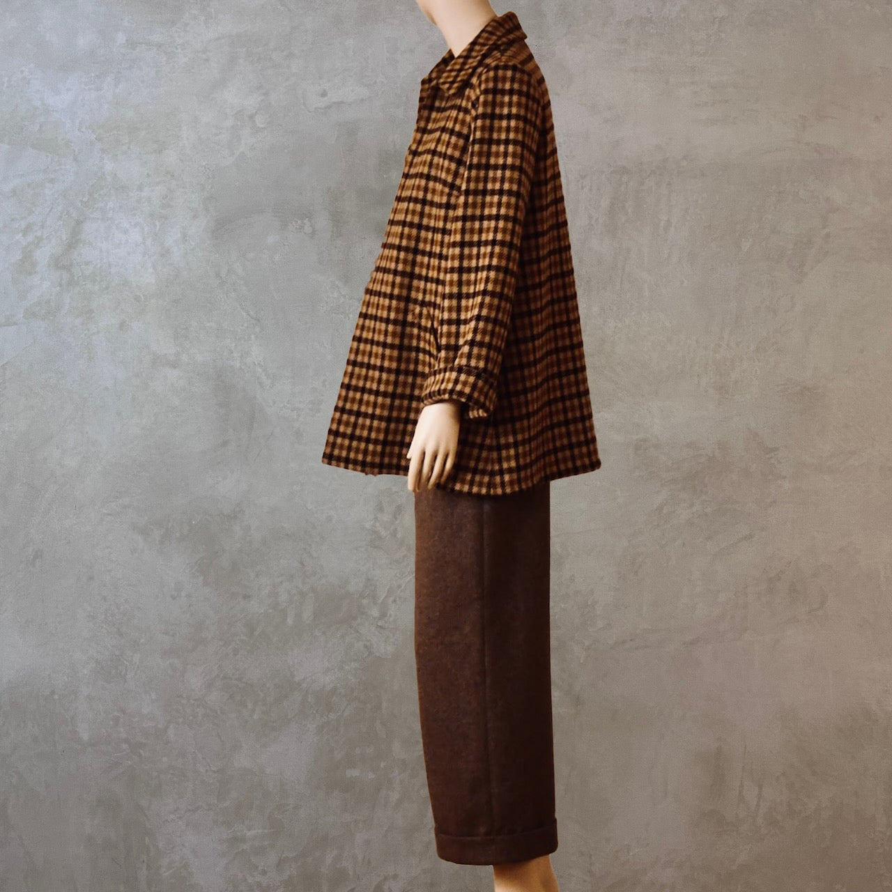 Tailored Swing Jacket in Fox Flannel Brown Gunclub Check, in pure merino wool. This bespoke jacket has rolled cuffs and a textured finish and a flared silhouette. Shown side on. Handmade in Britain.