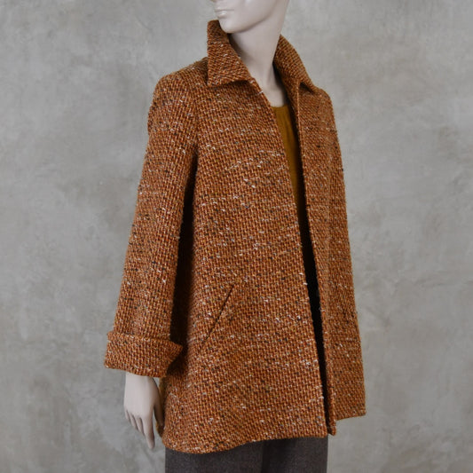 Mid length swing jacket in burnt orange Linton Tweeds wool boucle. Handmade in London, this jacket has fold back cuffs, two slanted pockets to the front and a lift up collar. Easy to wear, it is available in sizes 6 to 20 and bespoke sizing. 