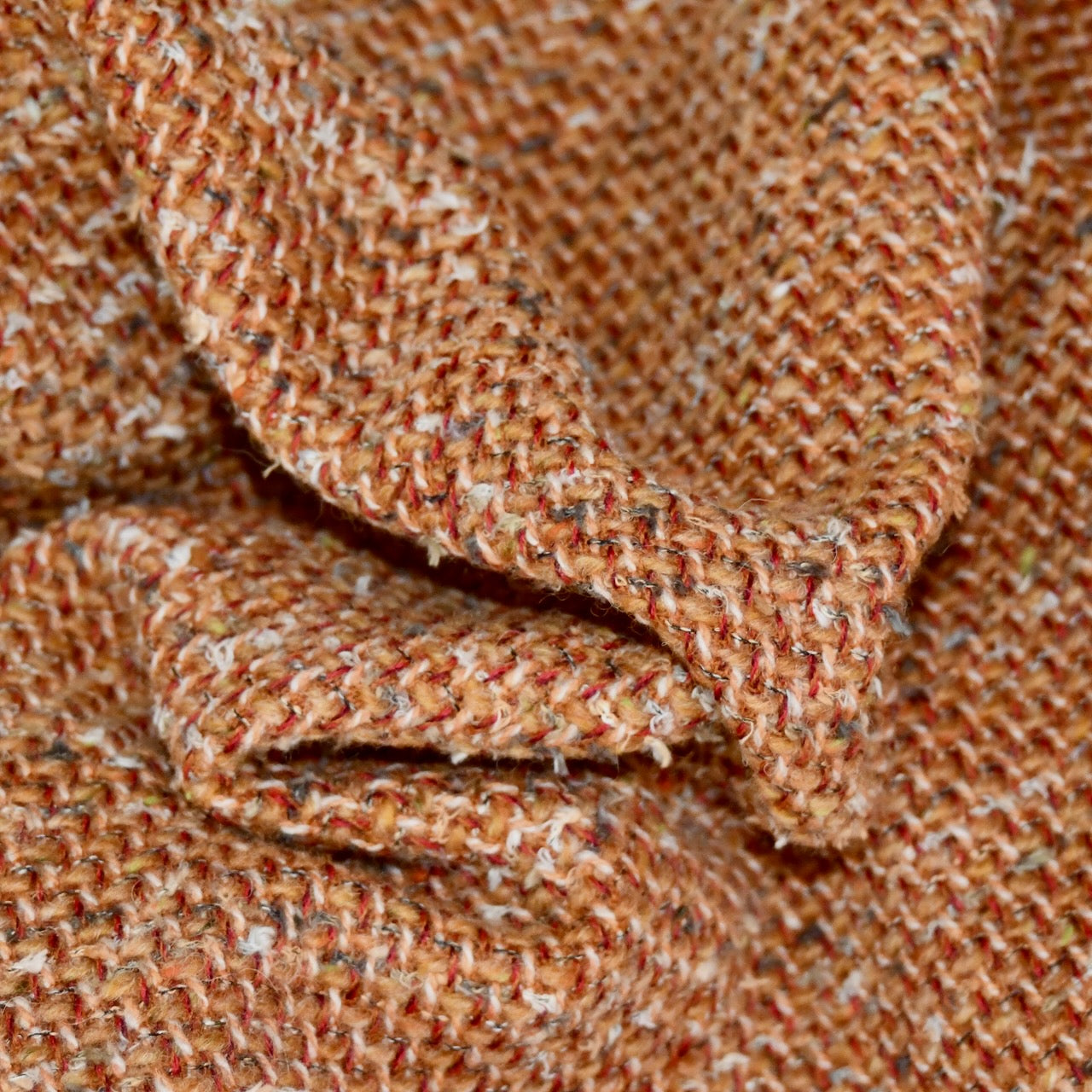 Fabric detail of Orange Linton Tweeds Boucle offered by EdNerat for bespoke coats, capes and jackets. Handmade in London. Woven in Carlisle.