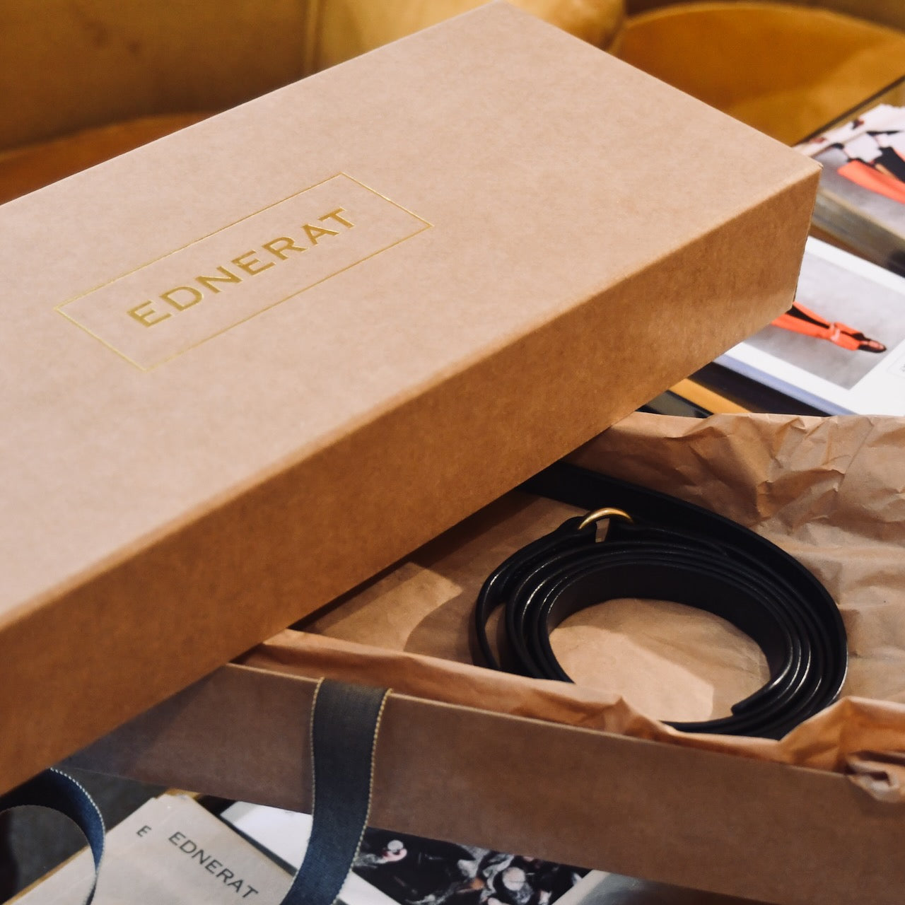 A brown EDNERAT box, slightly open to reveal the Black Double Wrap Belt - 200cm. The handmade belt is crafted from British saddle leather. Handmade in Britain.