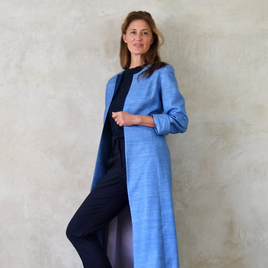 Tailored, Fitted Hourglass shaped coat in a summer-weight Silk Madras in Blue. This is a long-sleeved, calf-length blue summer coat with an hourglass shape. Shown from the back. A perfect summer coat for weddings and special occasions. Handmade in Britain.