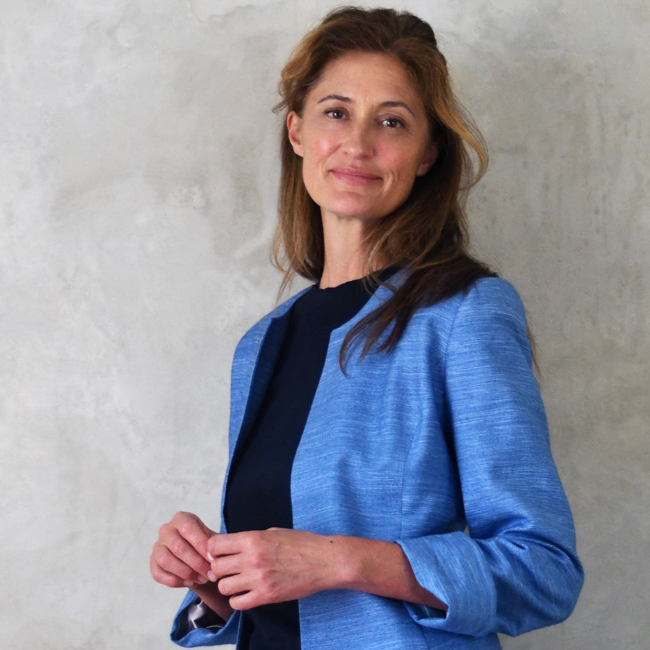 Tailored, Fitted Hourglass shaped coat in a summer-weight Silk Madras in Blue. This is a long-sleeved, calf-length blue summer coat with an hourglass shape. Shown on a model. A perfect summer coat for weddings and special occasions. Handmade in Britain.