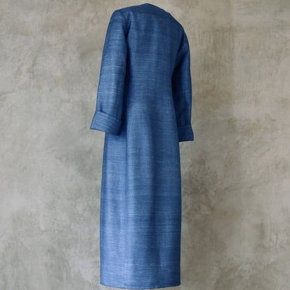Tailored, Fitted Hourglass shaped coat in a summer-weight Silk Madras in Blue. This is a long-sleeved, calf-length blue summer coat with an hourglass shape. Shown from the side-back. A perfect summer coat for weddings and special occasions. Handmade in Britain.