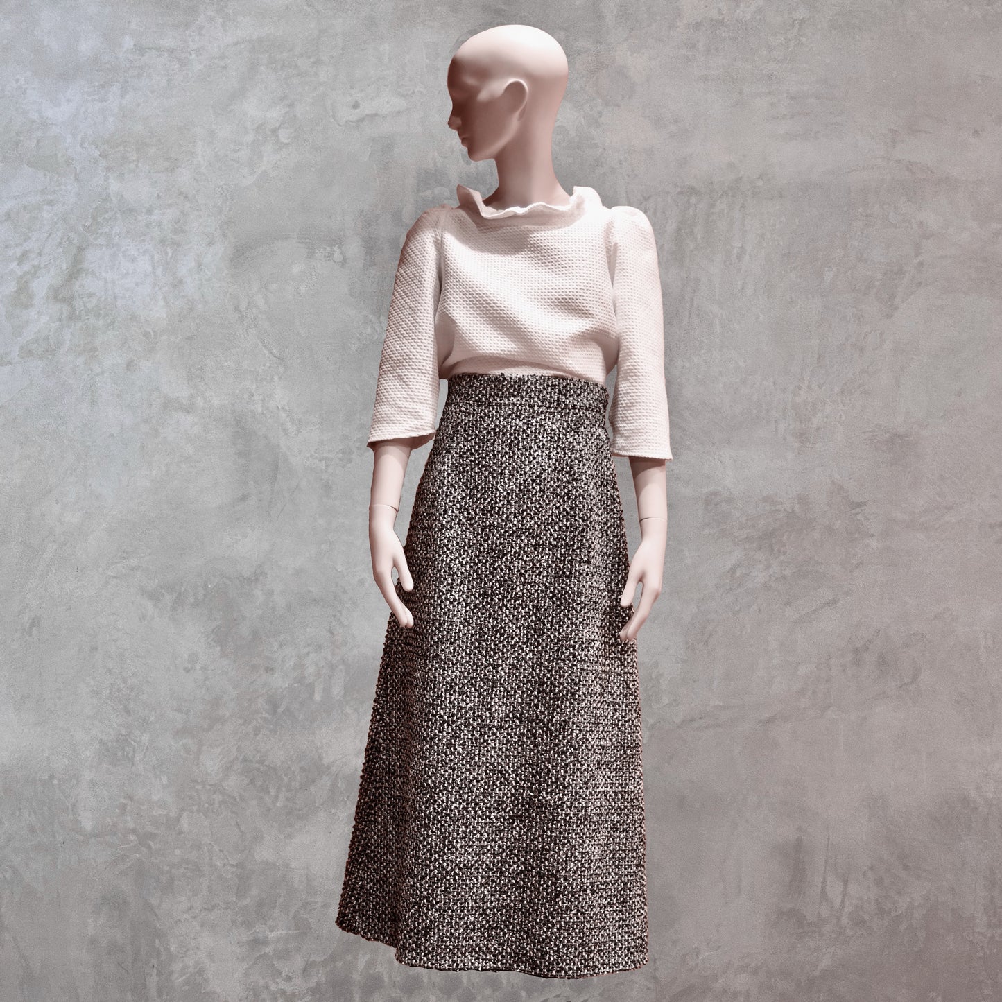 A Waisted A-Line Skirt in Linton Tweeds Boucle, styled with a textured white top. Handmade in Britain.