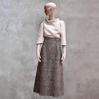 A Waisted A-Line Skirt in Linton Tweeds Boucle, styled with a textured white top. Handmade in Britain.