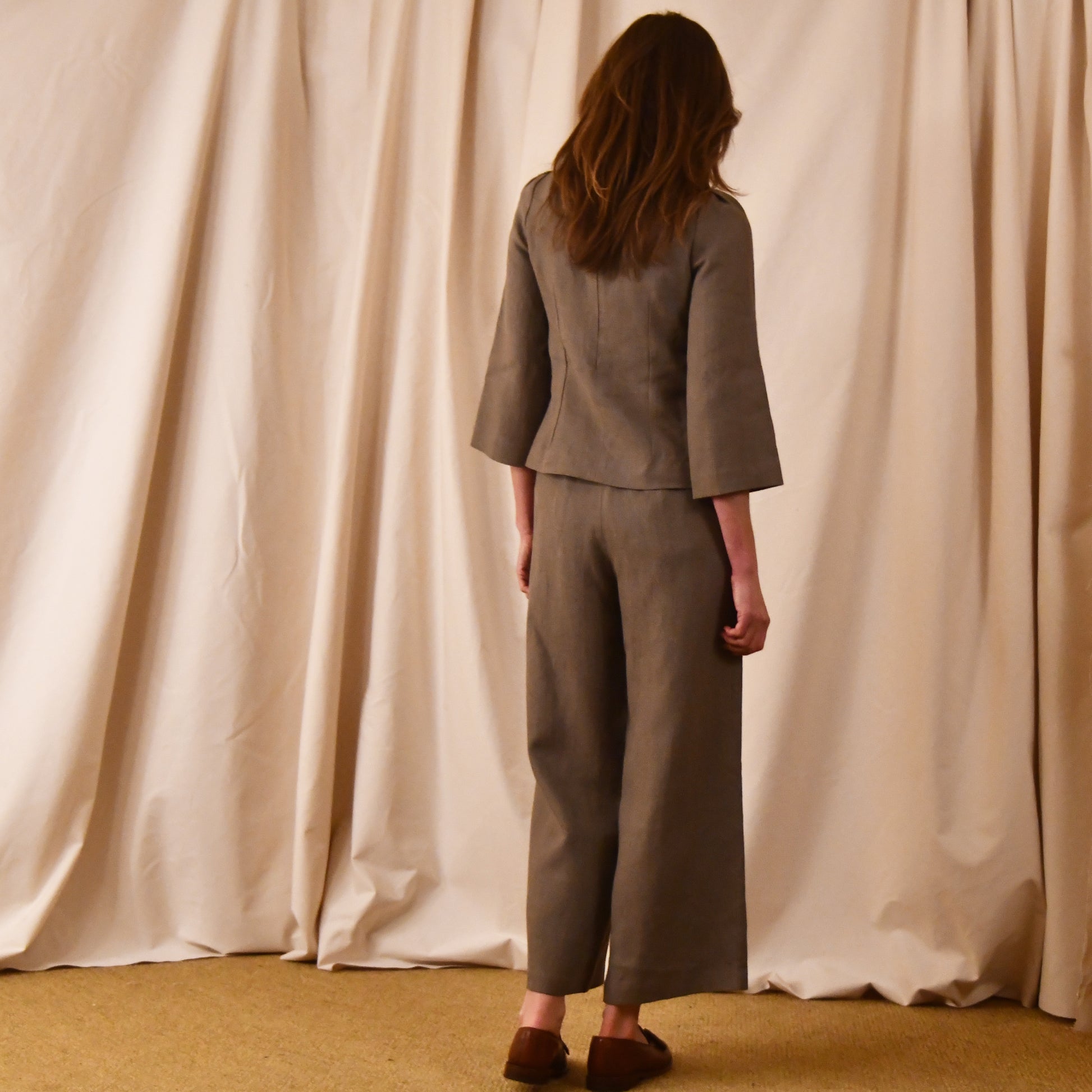 A Tailored Boat Neck Blouse in Brown Irish Linen. Fitted and elegant the top is shown over a matching loose fitting Linen Pants. Handmade in Britain. Rear View.