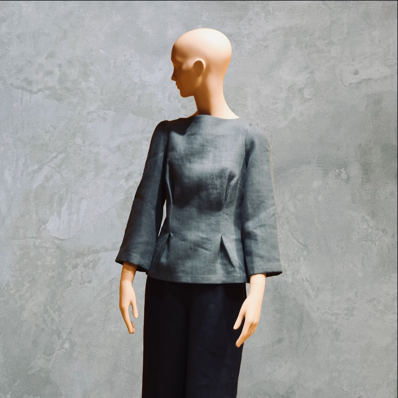 Bespoke Sea Blue Boat Neck Tailored Top  with three quarter sleeves in Slubby Irish Linen. Shown worn over trousers, three quarters view.
Handmade in Britain.