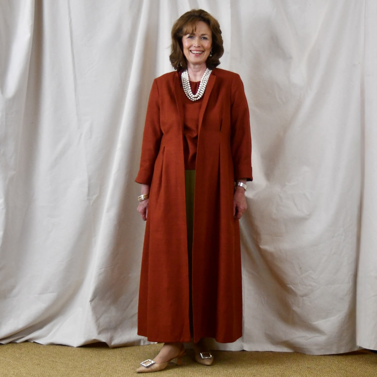 Fitted Occasion Coat in Summer Weight Silk Matka. A terracotta-coloured woven silk, falls gracefully from two front and rear dart details. Handmade in Britain.