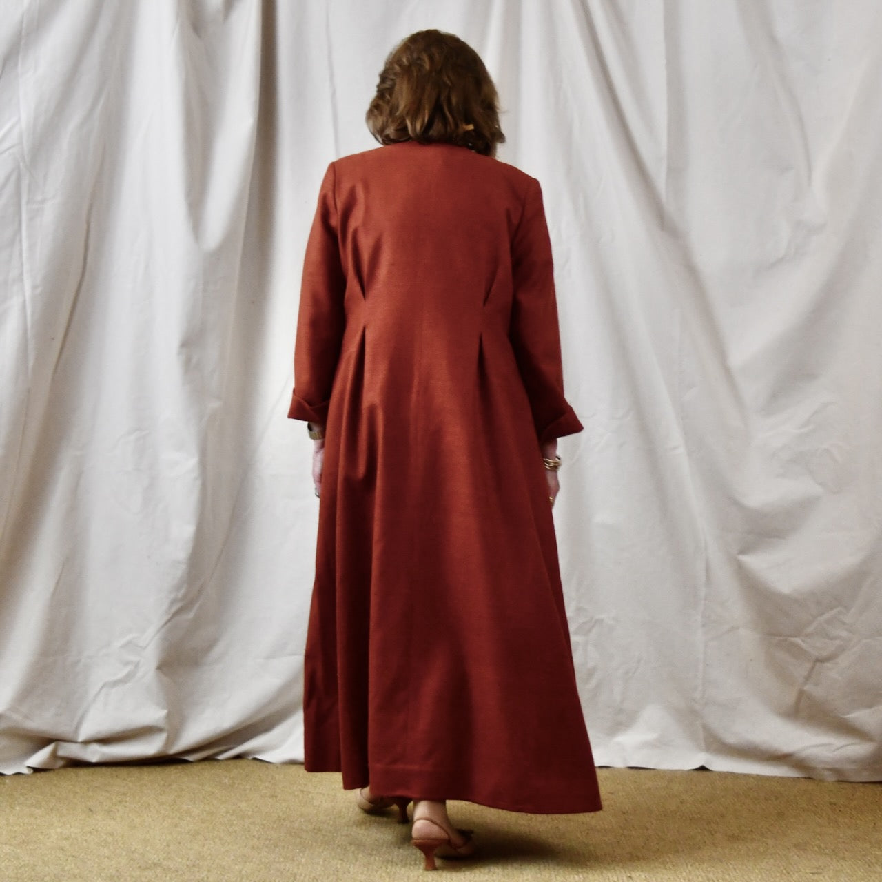 Fitted Occasion Coat in Summer Weight Silk Matka. A terracotta-coloured woven silk, falls gracefully from two front and rear dart details. Handmade in Britain. Rear View.