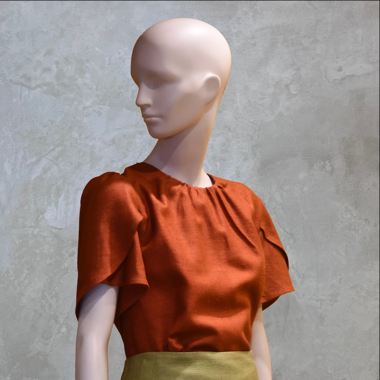 A Tulip Sleeve Blouse in Burnt Brick Silk Matka with a light olive-green skirt. Handmade in Britain.