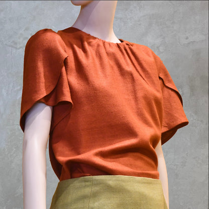 A Tulip Sleeve Blouse in Burnt Brick Silk Matka paired with an olive-green skirt. Handmade in Britain.