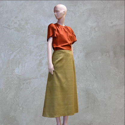 ATulip Sleeve Blouse in Burnt Brick Silk Matka with a high-waisted, ankle-length olive green skirt. Handmade in Britain. 