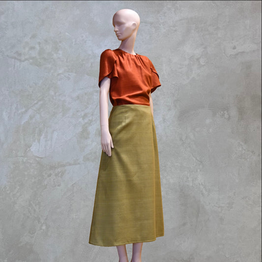ATulip Sleeve Blouse in Burnt Brick Silk Matka with a high-waisted, ankle-length olive green skirt. Handmade in Britain. 