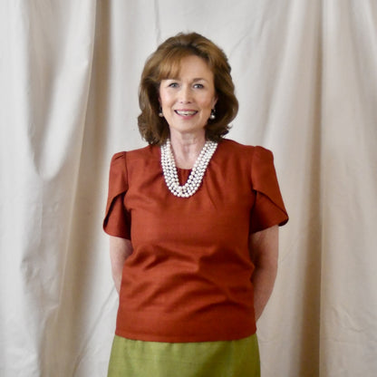A Tulip Sleeve Blouse in Burnt Brick Silk Matka paired with an olive-green skirt. Handmade in Britain.