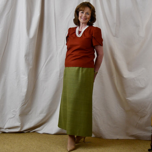 A Tulip Sleeve Blouse in Burnt Brick Silk Matka paired with an olive-green skirt. Handmade in Britain.