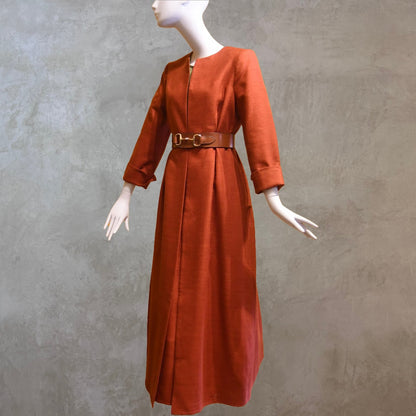 Tailored, Fitted Hourglass shaped coat in a summer-weight Silk in a terracotta colour. This is a three-quarter-sleeved, calf-length blue summer coat with an hourglass and skirted shape. Shown from the side-front, belted. A perfect summer coat for weddings and special occasions. Handmade in Britain.