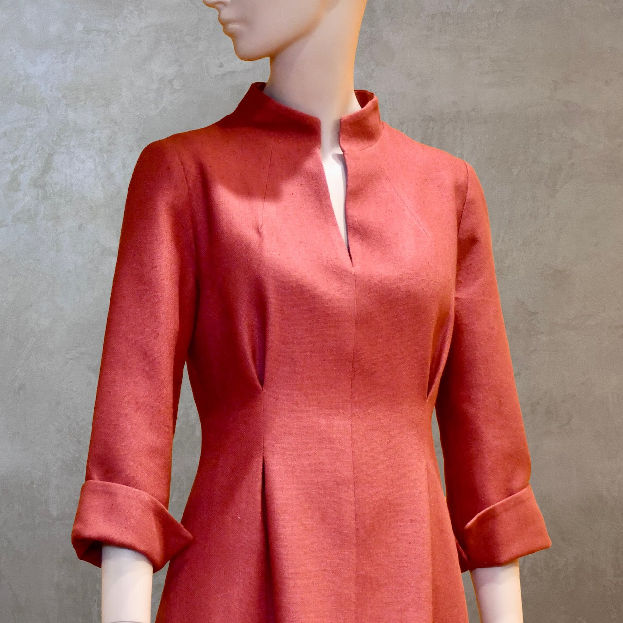 Collar and waist detail on formal summer dress in pure silk. Handmade in London this pink dress has a nipped in waist, mid length sleeves, turn back cuffs and gently flattering inverted darts at the rear. Slits to the side and an open neckline with a Nehru collar. 
